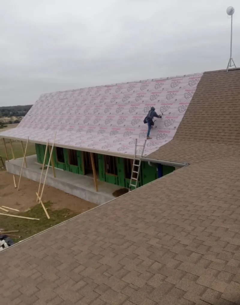 Worker preparing underlayment for a metal roof installation in Ballwin